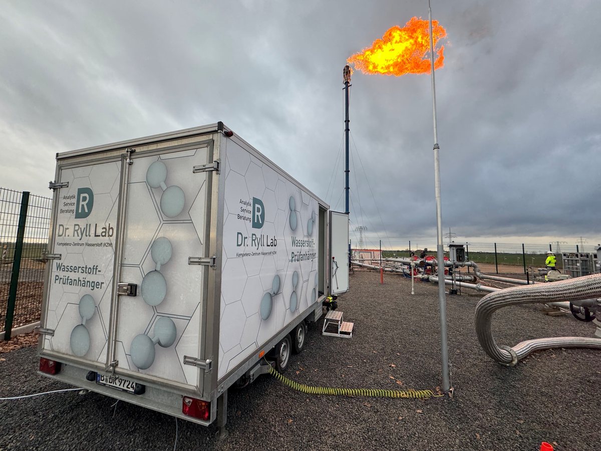 Wasserstoff-Prüfanhänger der Dr. Ryll Lab GmbH an einer Gasstation, daneben eine brennende Fackel